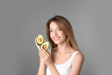 Portrait of young beautiful woman with ripe delicious avocado on color background