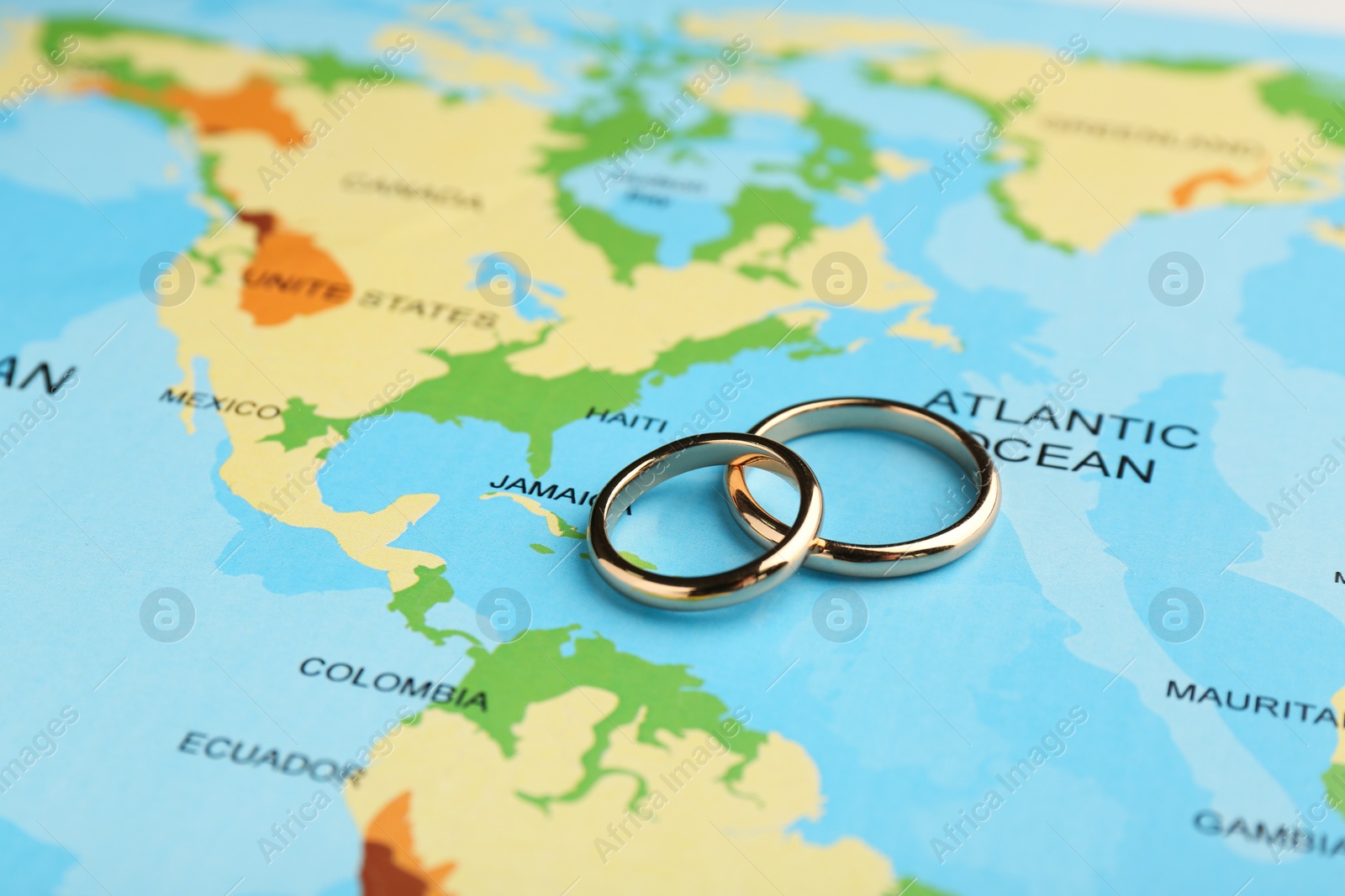 Photo of Honeymoon concept. Two golden rings on world map, closeup