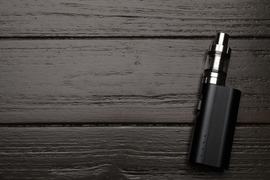 Photo of Electronic cigarette on black wooden table, top view with space for text. Smoking alternative