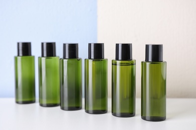 Photo of Row of mini bottles with cosmetic products on white table