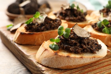 Photo of Delicious bruschettas with truffle sauce and microgreens on wooden table, closeup