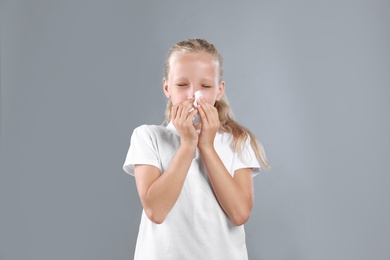 Little girl suffering from allergy on grey background