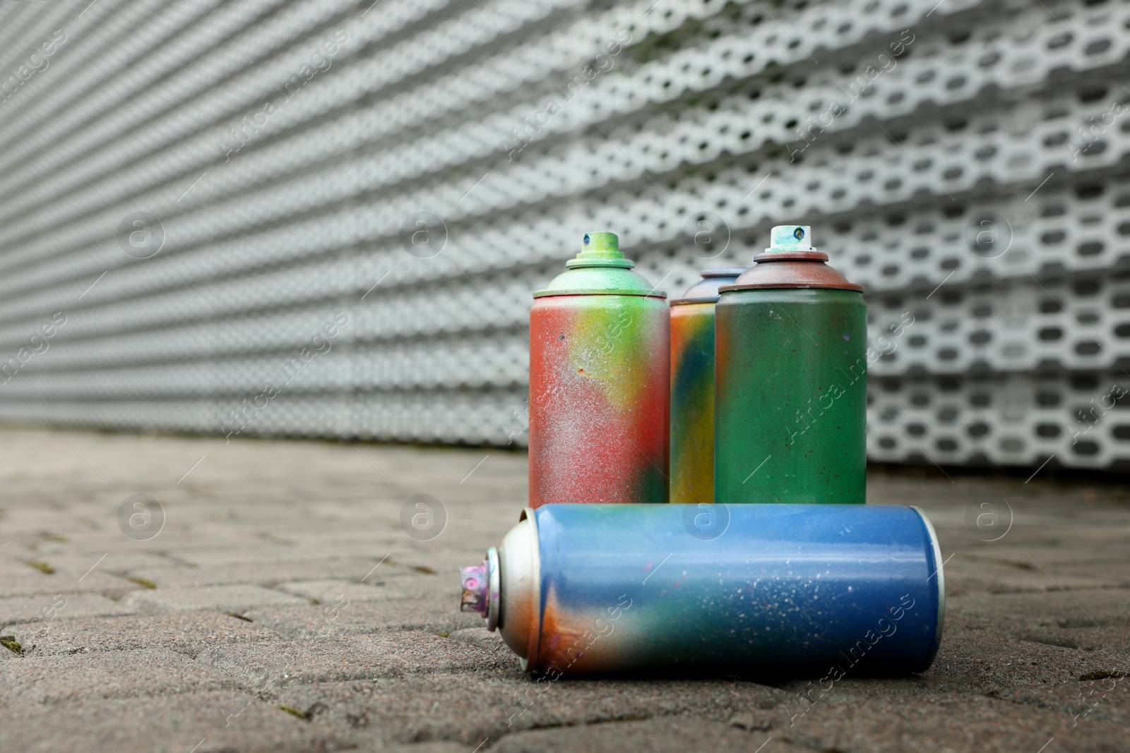 Photo of Used cans of spray paints on pavement, space for text