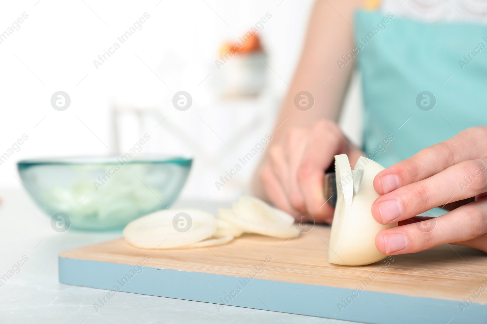 Photo of Woman cutting onion on wooden board, closeup