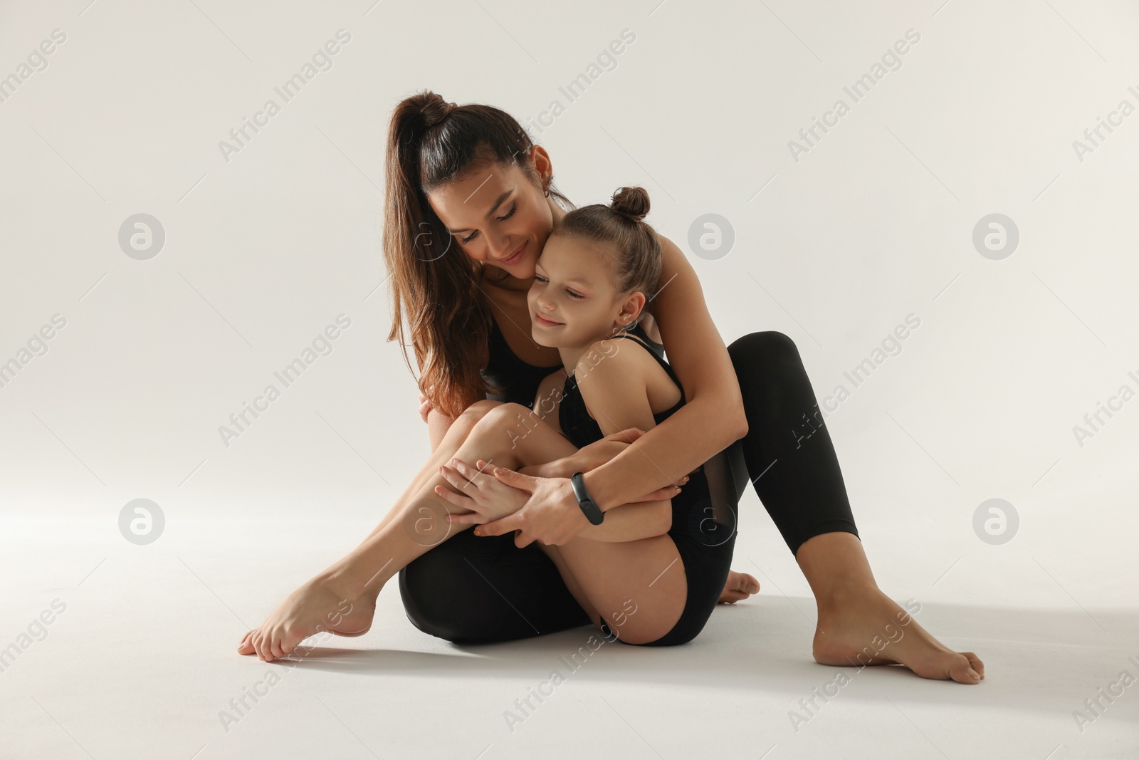 Photo of Little gymnast and her coach sitting on white background
