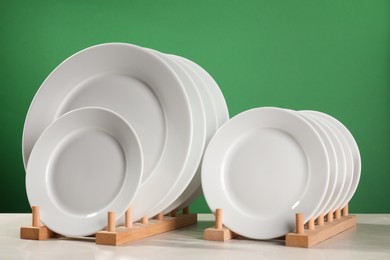 Photo of Many clean plates on white table against green background