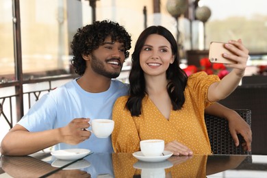 Photo of International dating. Happy couple taking selfie in restaurant