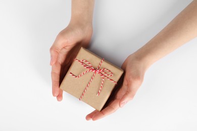 Woman holding parcel wrapped in kraft paper on white background, top view