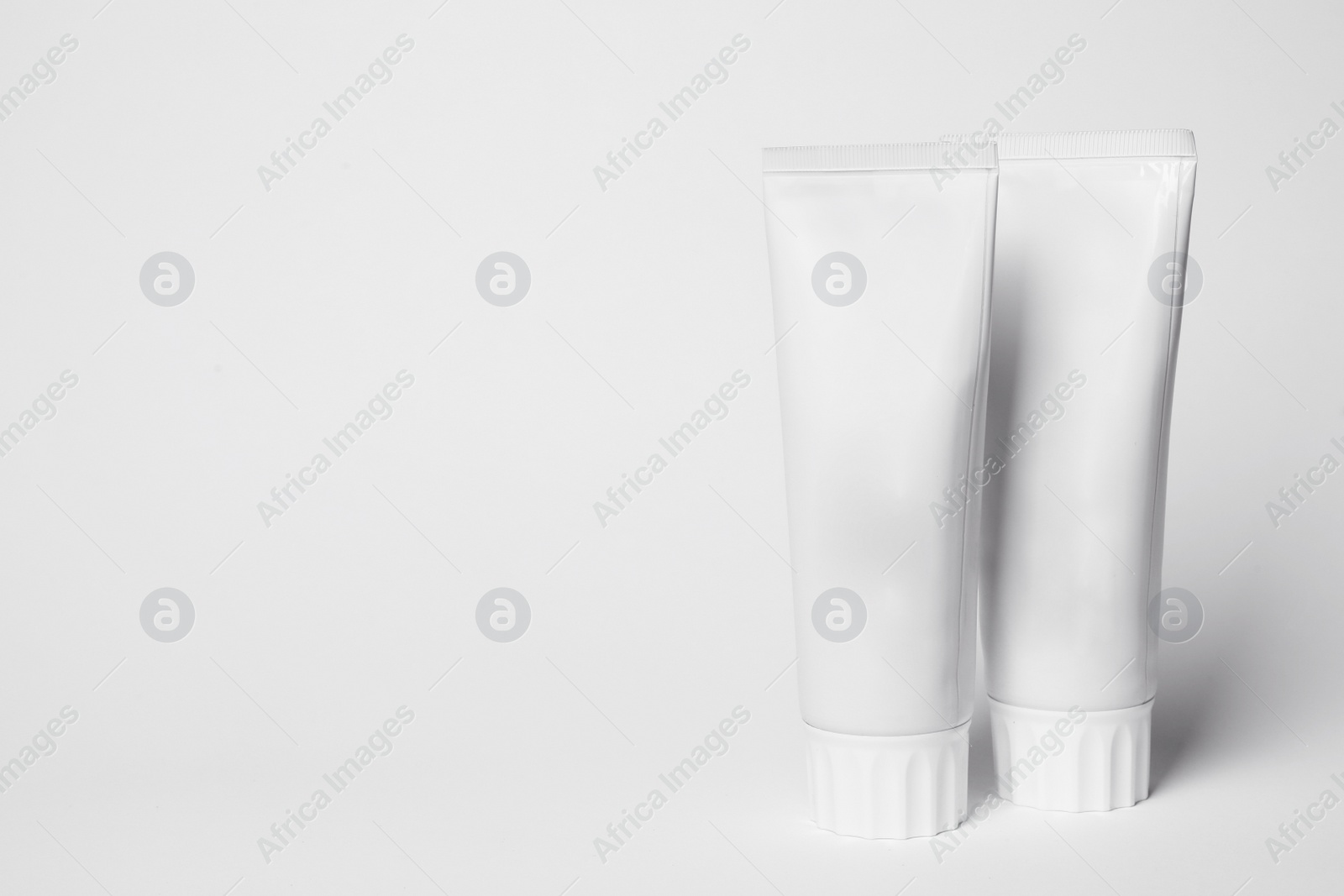 Photo of Blank tubes of toothpaste on white background. Space for text