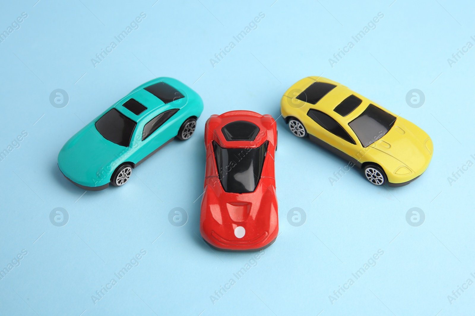 Photo of Different bright cars on light blue background. Children`s toys