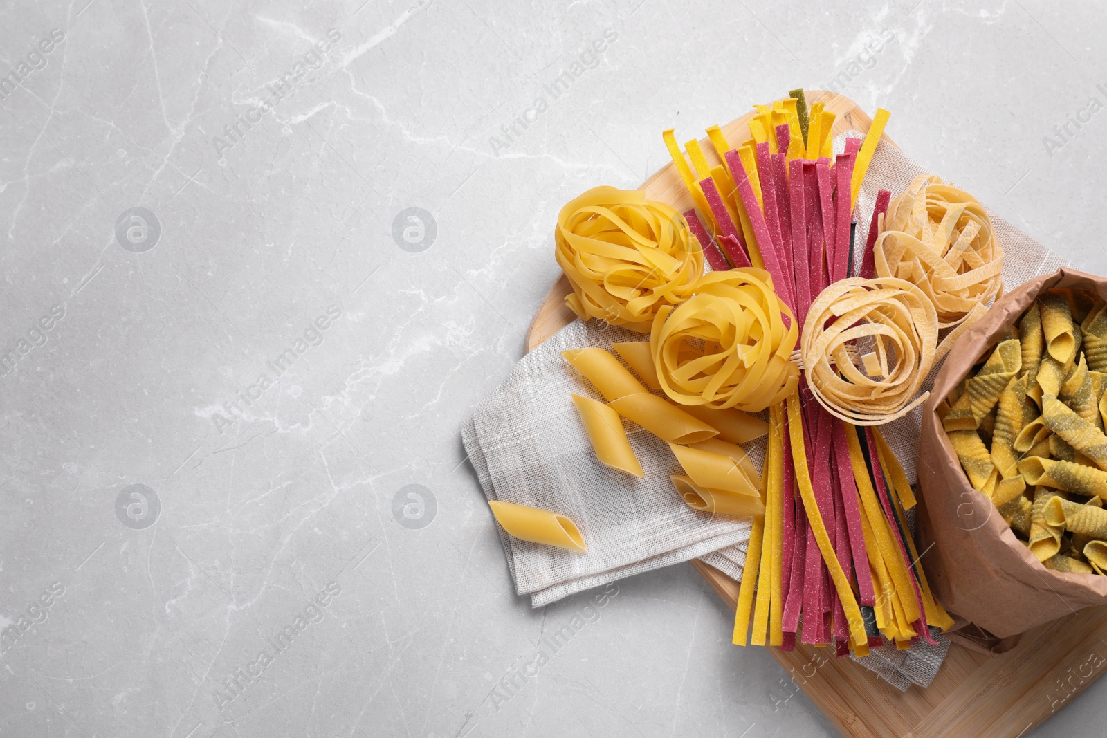 Photo of Different types of pasta on light grey marble table, top view. Space for text