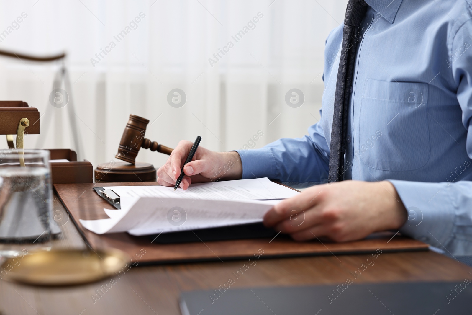 Photo of Lawyer working with documents at wooden table indoors, closeup