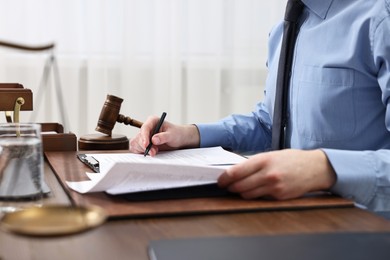 Photo of Lawyer working with documents at wooden table indoors, closeup