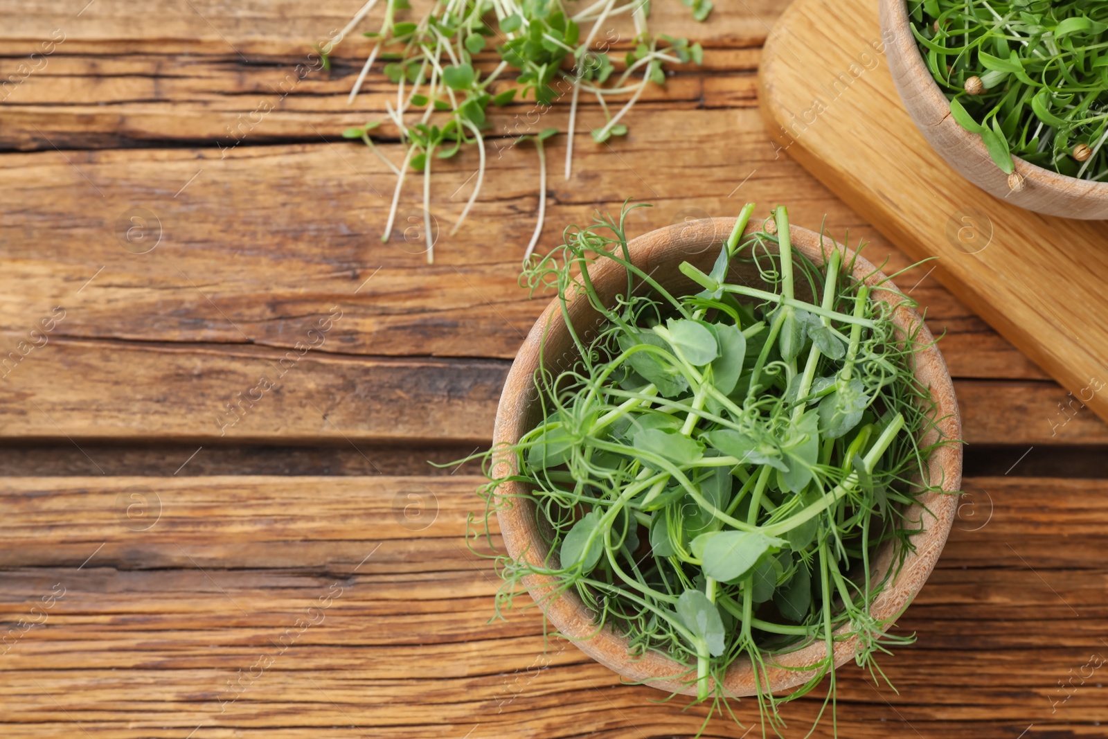 Photo of Fresh microgreen on wooden table, flat lay. Space for text