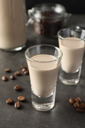 Coffee cream liqueur in glasses and beans on grey table, closeup