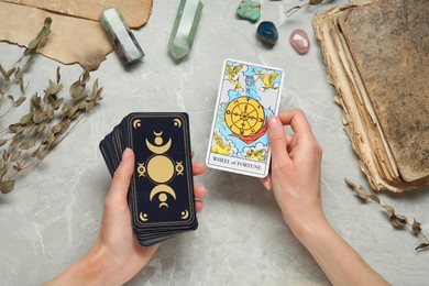 Woman with tarot cards at grey table, closeup