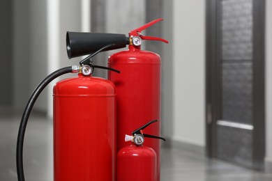Photo of Three red fire extinguishers in hall. Space for text