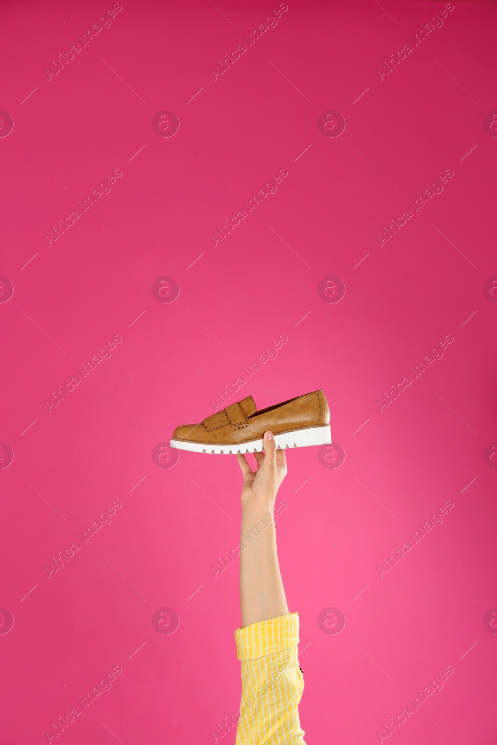 Photo of Young woman holding comfortable shoe on pink background, closeup