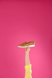 Photo of Young woman holding comfortable shoe on pink background, closeup