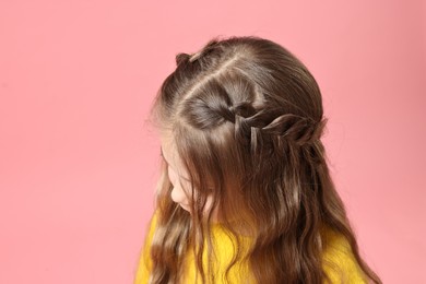 Photo of Cute little girl with braided hair on pink background