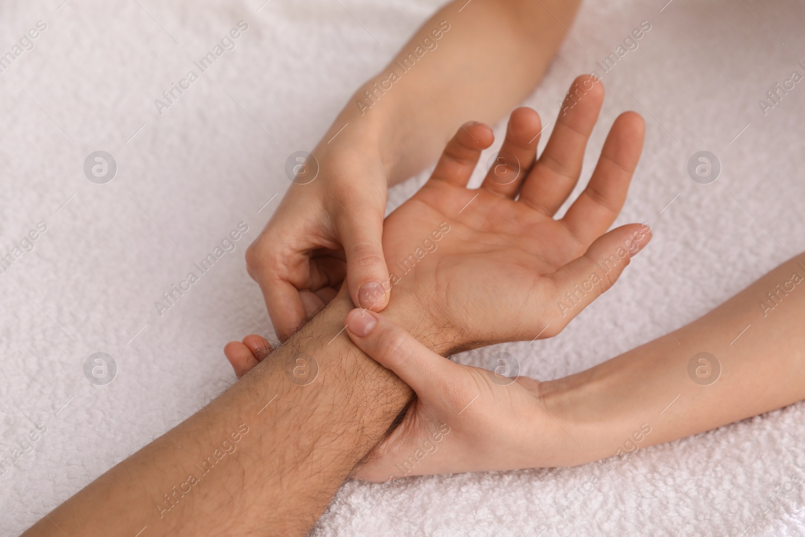 Photo of Man receiving hand massage on soft towel, closeup