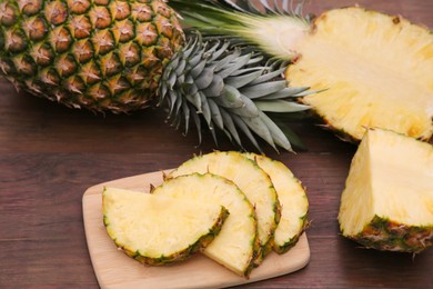 Photo of Cut and whole ripe pineapples on wooden table