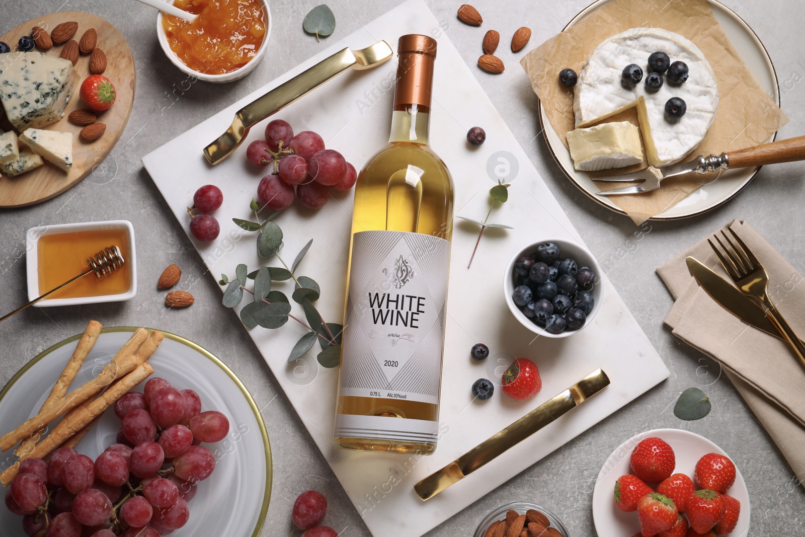 Photo of Flat lay composition with bottle of white wine and snacks on grey table