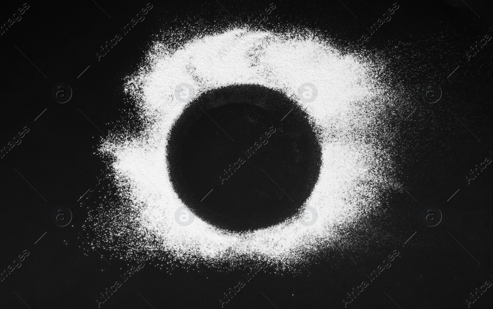 Photo of Round frame made of flour on black table, top view. Space for text