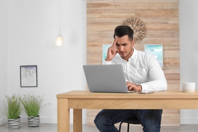 Photo of Portrait of handsome young man with laptop in office