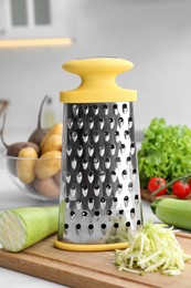 Photo of Grater and fresh zucchini on white table in kitchen
