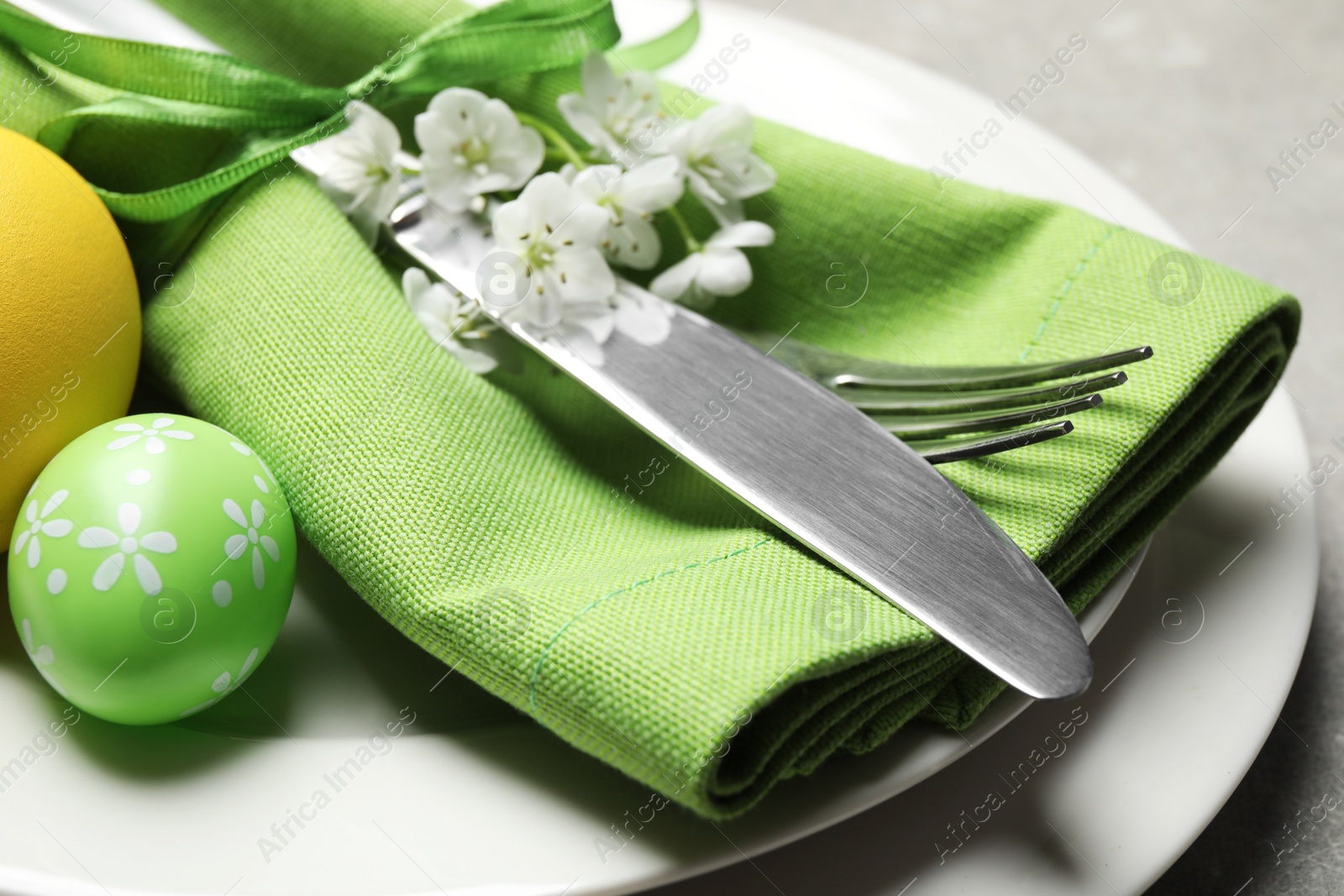 Photo of Festive Easter table setting with floral decor on grey background, closeup