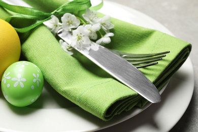 Festive Easter table setting with floral decor on grey background, closeup