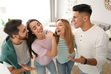 Happy friends singing karaoke together at home