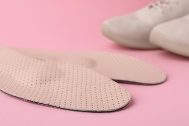 Photo of Orthopedic insoles and shoes on pink background, closeup