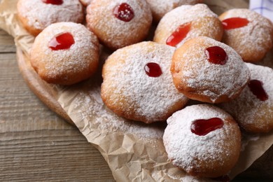 Photo of Hanukkah donuts with jelly and powdered sugar on wooden table, closeup
