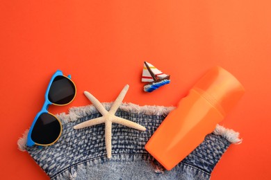 Flat lay composition with bottle of sunscreen on coral background. Space for text