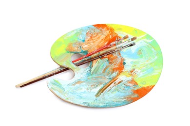 Photo of Artist's palette with mixed paints and brushes isolated on white