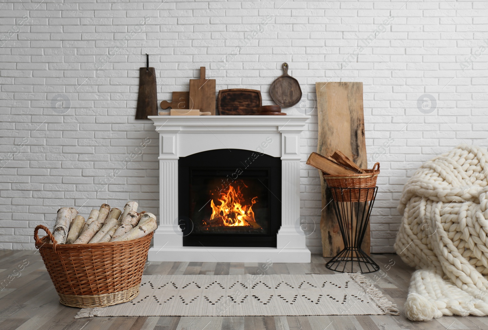 Photo of Wicker baskets with firewood and white fireplace in cozy living room