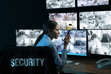 Photo of Security guard with portable transmitter monitoring modern CCTV cameras at night
