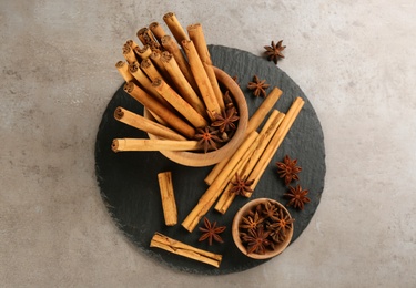 Photo of Aromatic cinnamon sticks and anise on grey table, flat lay
