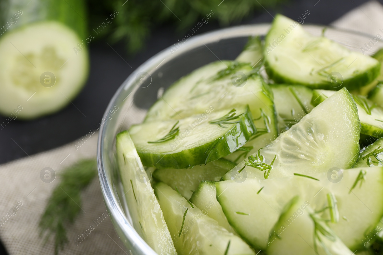 Photo of Cut cucumber with dill in glass bowl on table, closeup