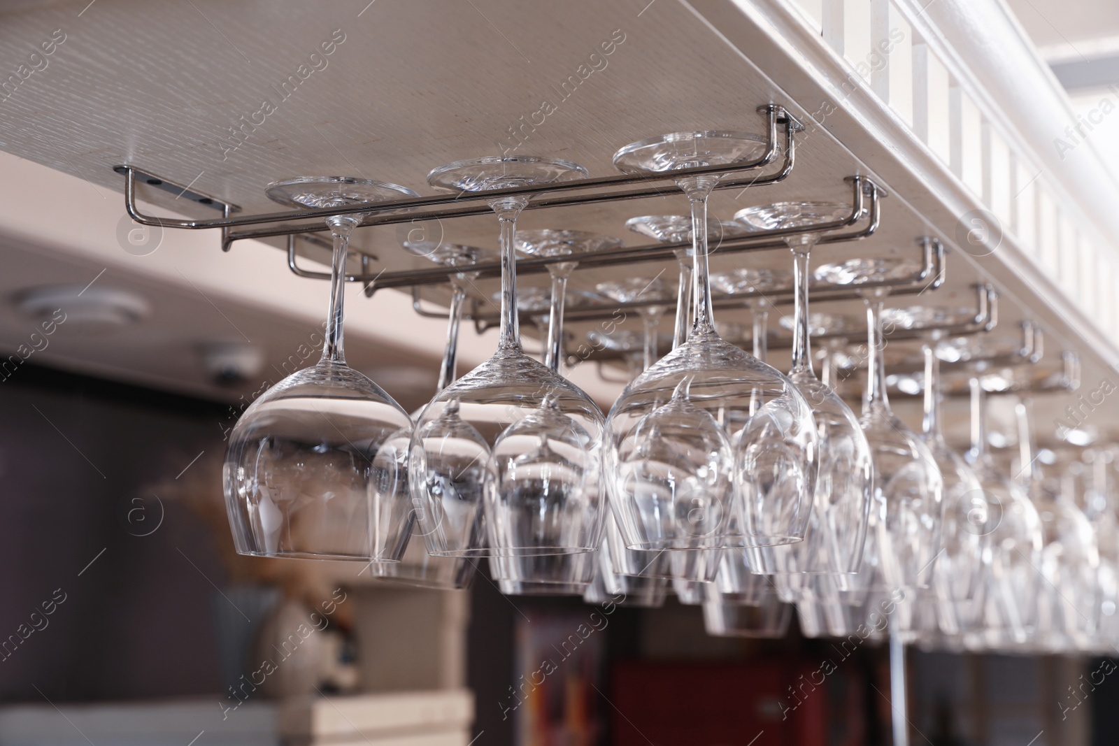 Photo of Set of empty clean glasses on bar racks