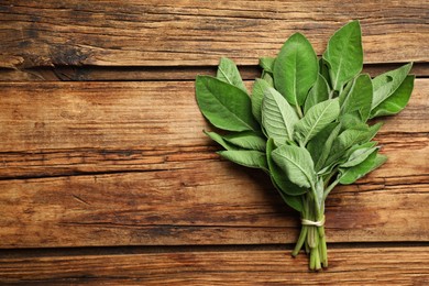 Photo of Bunch of fresh sage leaves on wooden table, top view. Space for text