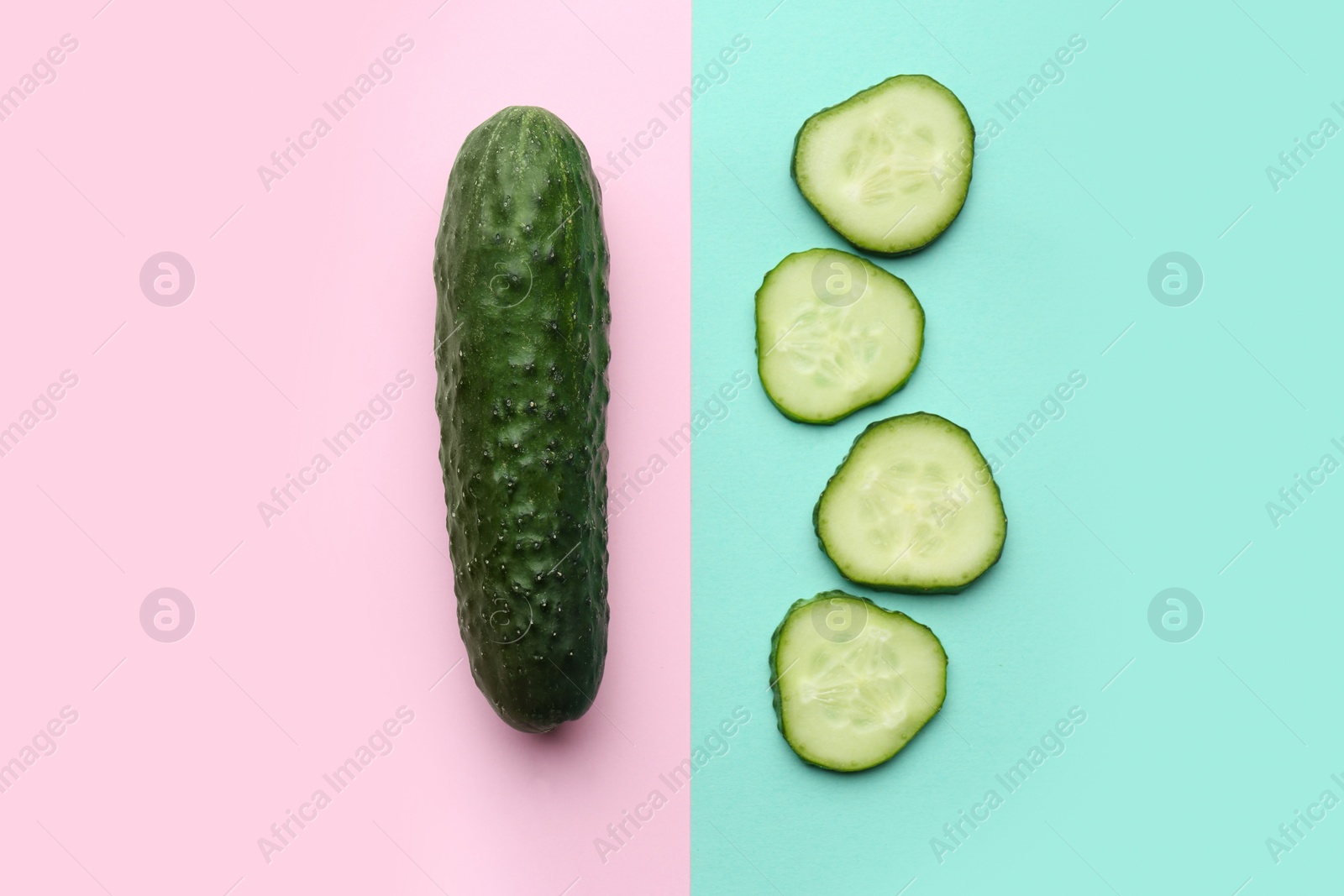 Photo of Whole and cut cucumbers on color background, flat lay