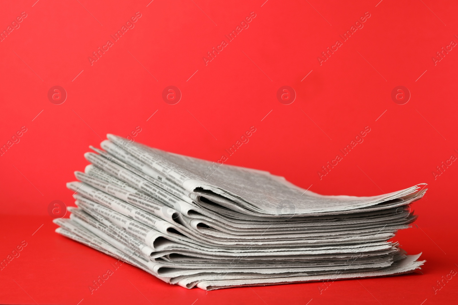 Photo of Stack of newspapers on red background. Journalist's work