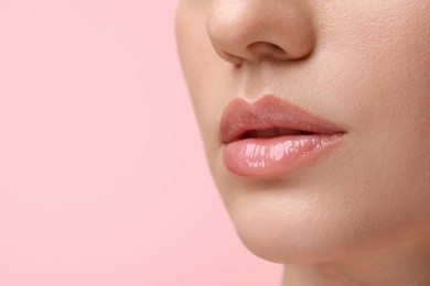 Photo of Woman wearing beautiful lip gloss on pink background, closeup. Space for text