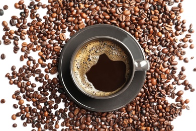 Photo of Roasted coffee beans and cup of hot beverage on white background, top view