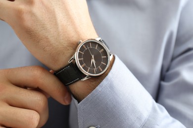 Man wearing luxury wrist watch with leather band, closeup