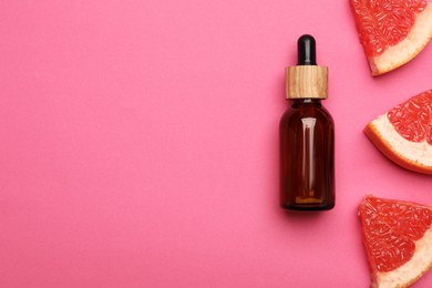 Photo of Bottle of citrus essential oil and fresh grapefruit slices on pink background, flat lay. Space for text