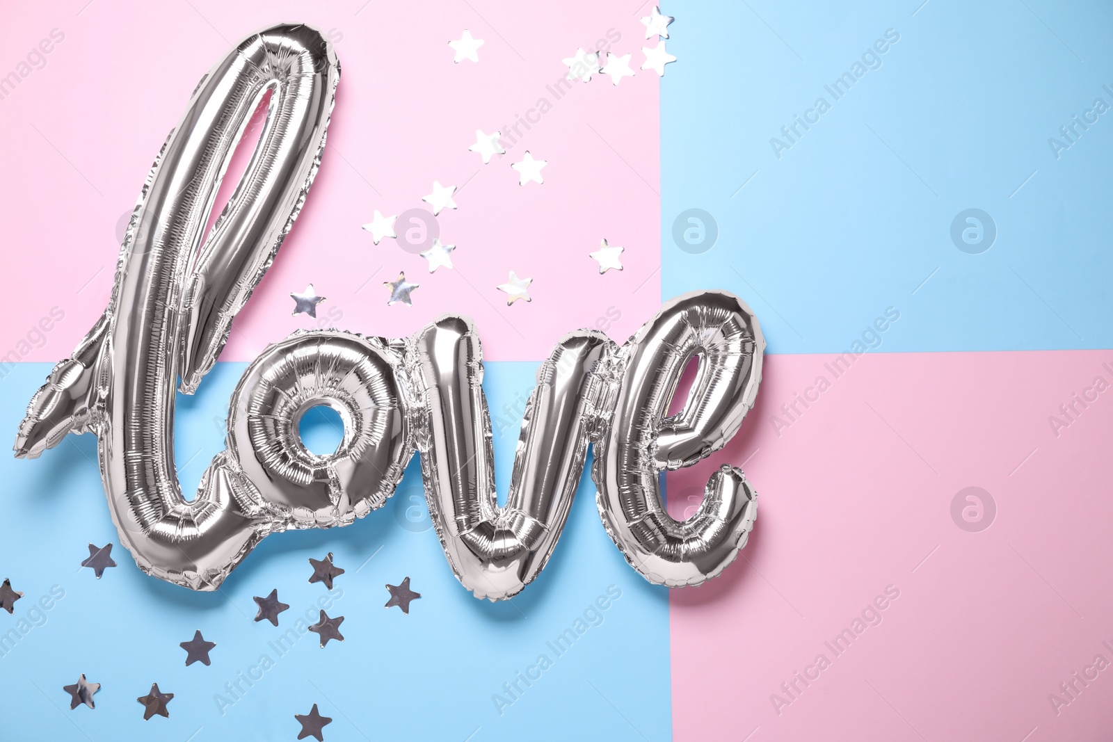 Photo of Foil balloon in shape of word LOVE on color background, above view
